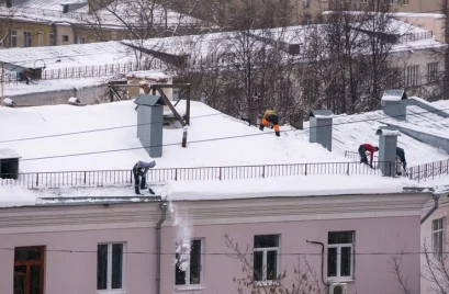 team-male-workers-clean-roof-building-from-snow-with-shovels-securing-belts-mantra_197589-3136